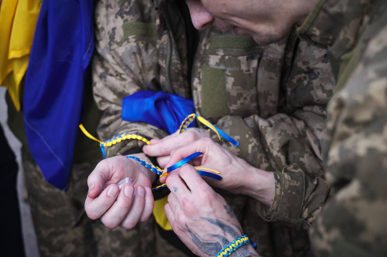 Полонені в'яжуть один одному синьо-жовті браслети