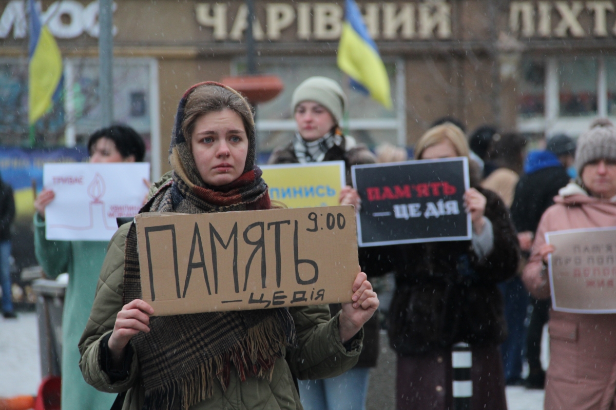 Жінка з плакатом з надписом "Пам'ять"