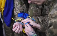 Полонені в'яжуть один одному синьо-жовті браслети