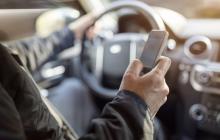 Водій за кермом користується телефоном