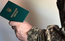 Зображення військового квитка, який тримають у руці.